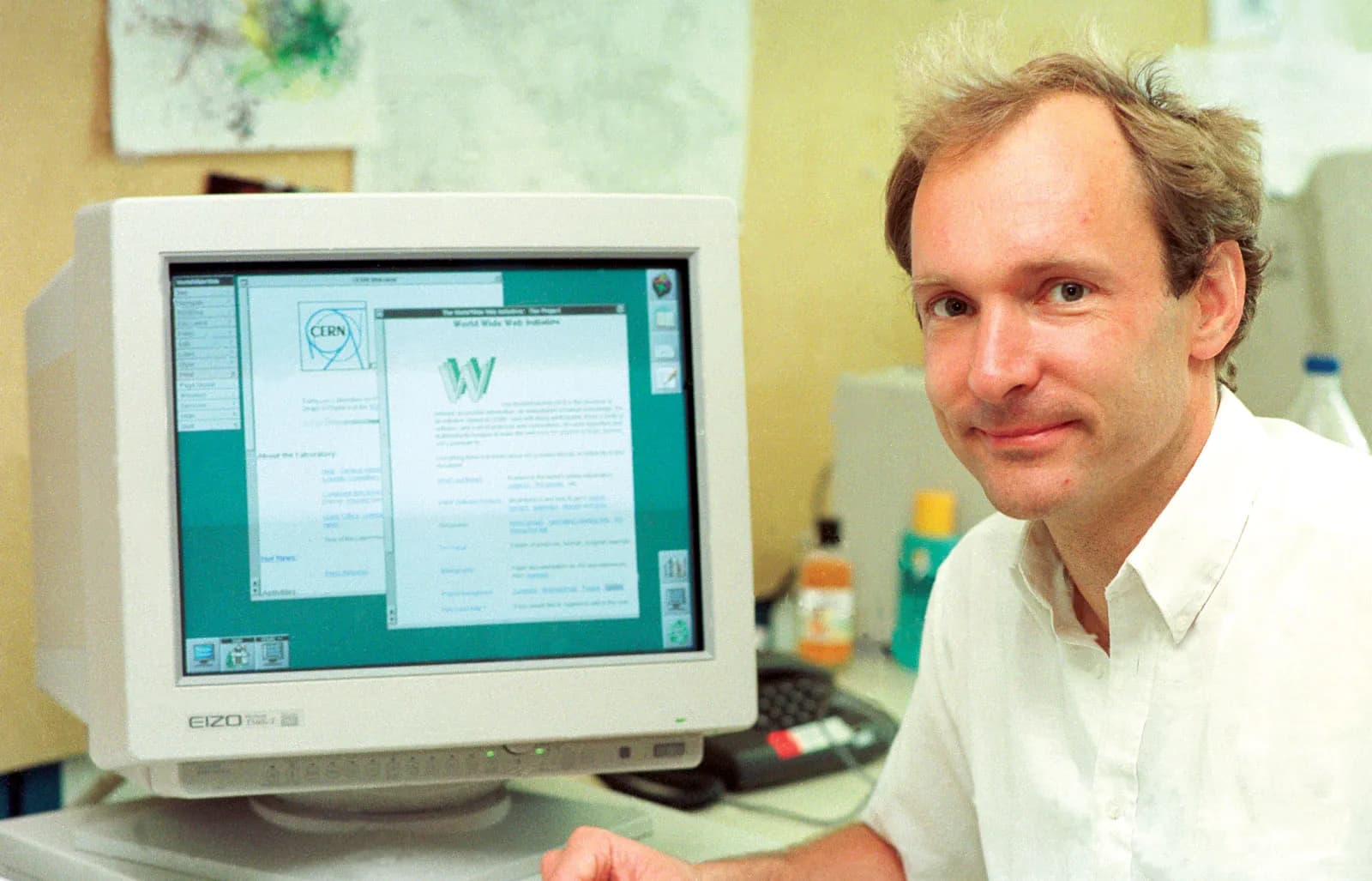 Tim Berners-Lee seated beside an early 1990s computer monitor displaying the first World Wide Web browser at CERN