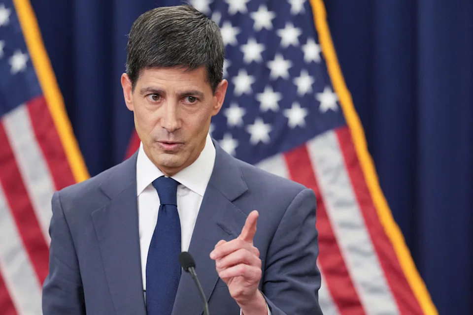 Federal Reserve Chair Kevin Warsh speaking at a press conference in front of American flags